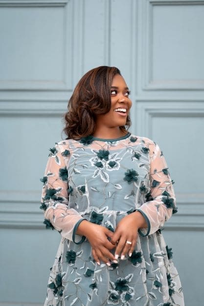 Shontae Buffington in front of green door wearing a hand sewn green dress Simplicity 8545 with hands in front