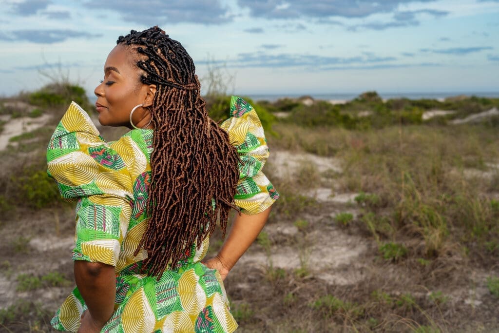 African American woman wearing McCalls 8146 pattern in green Ankara in an open field