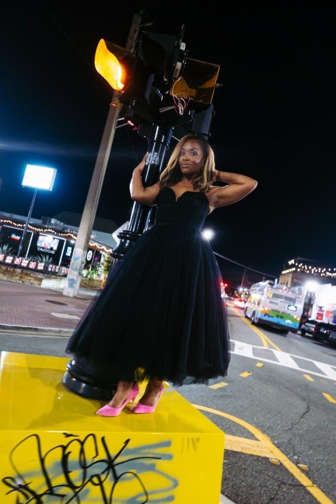 Close-up of the bright pink heels contrasting sharply with the long black tulle skirt, highlighting the unexpected styling choice.