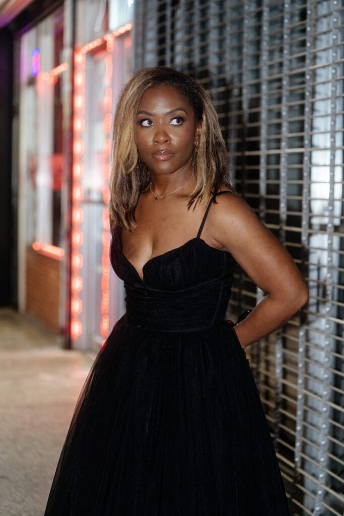 Shontae modeling her DIY designer dress, featuring a black structured corset bodice with delicate spaghetti straps, looking to the side in an urban setting.