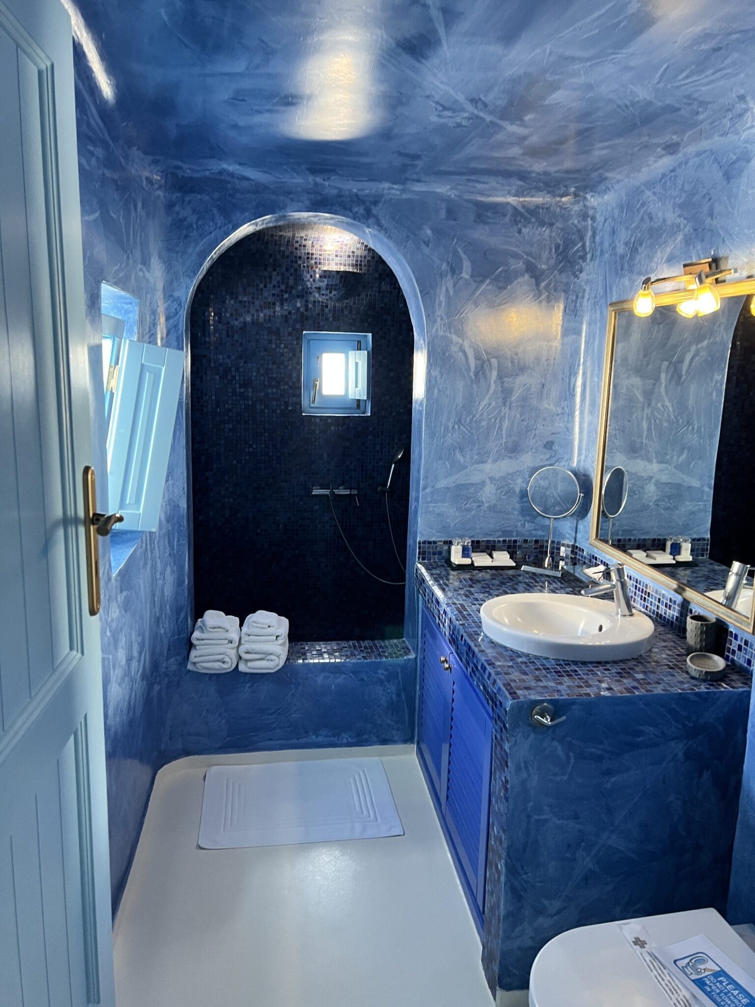 Blue mosaic cave bathroom in Greece perfectly suited for travel shower essentials