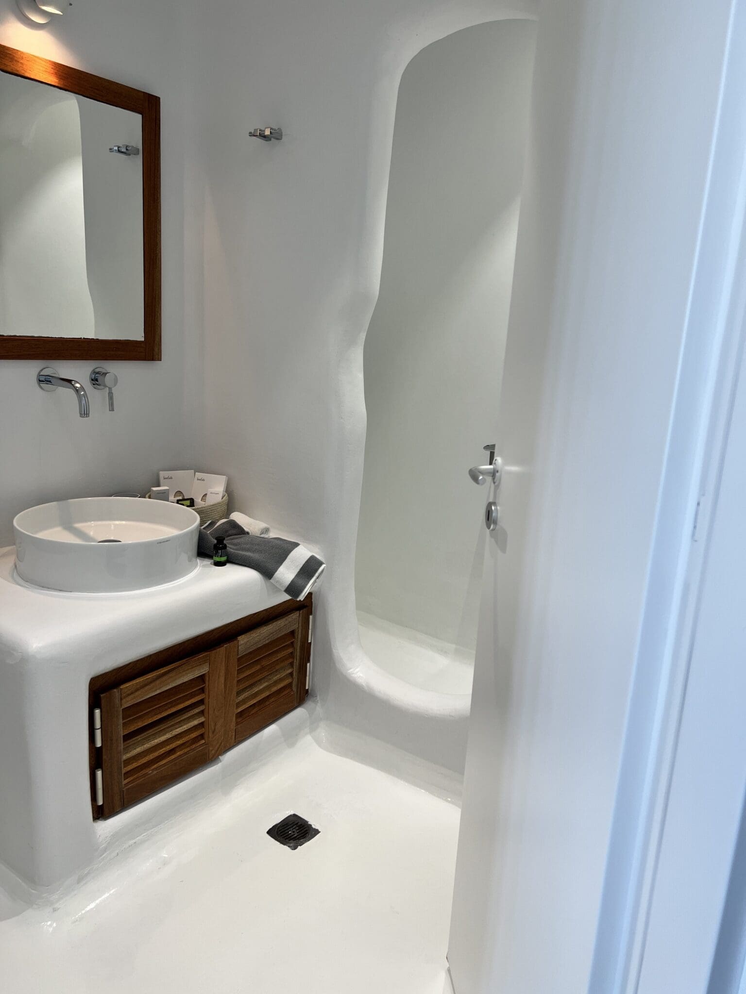 Minimalist white cave bathroom in Greece showcasing the need for travel shower essentials