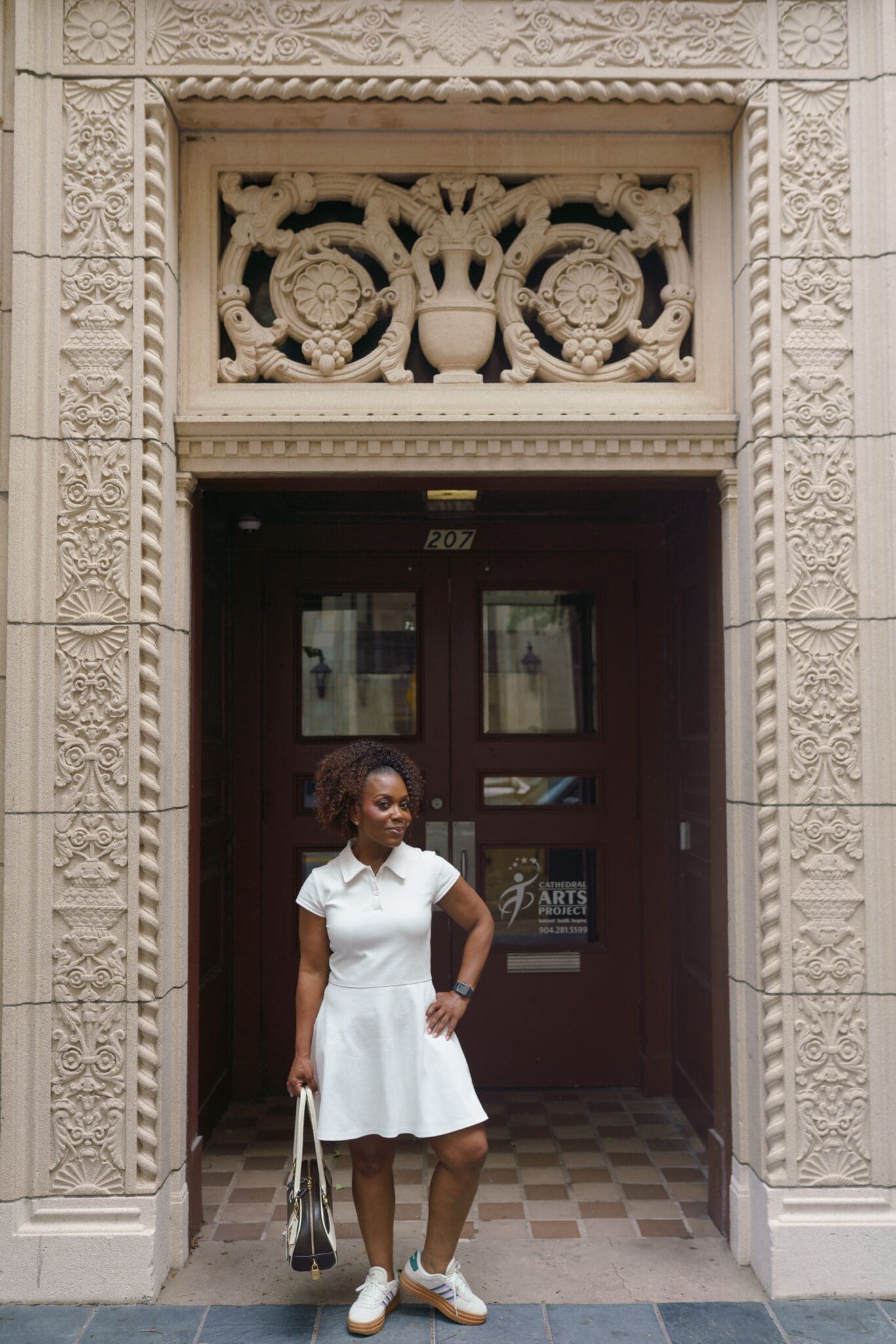Dr. Shontae Buffington showcasing a structured cream knit polo mini dress silhouette while walking down the street.